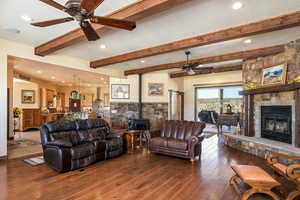 Living room featuring a wood stove, ceiling fan, hardwood / wood-style floors, beamed ceiling, and recessed lighting