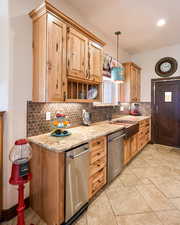 Kitchen featuring dishwasher, decorative backsplash, light stone counters, hanging light fixtures, and open shelves