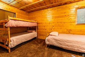 Bedroom with carpet floors, wood ceiling, and wood walls