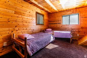 Carpeted bedroom with wood ceiling and wooden walls