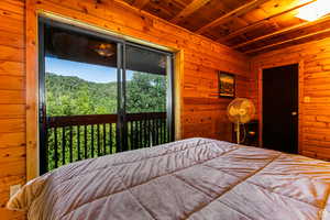 Bedroom featuring wooden ceiling, wood walls, and access to exterior