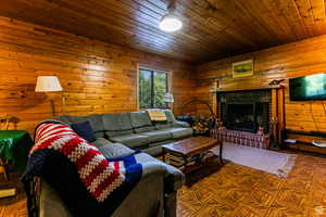 Living area with wood walls, a brick fireplace, and wood ceiling