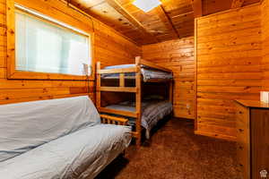 Carpeted bedroom with wood ceiling and wooden walls