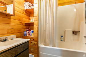 Bathroom featuring shower / bath combo, vanity, and wood walls
