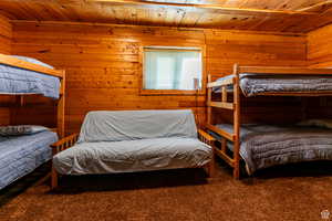 Bedroom with wood ceiling, wood walls, and carpet floors