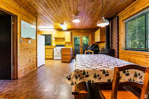 Bedroom with freestanding refrigerator, french doors, wooden walls, wood ceiling, and a wood stove