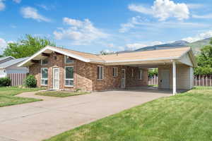 View of front facade with a carport, concrete driveway, brick siding, and a mountain view