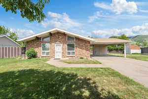 Mid-century home with brick siding, concrete driveway, an attached carport, and a mountain view