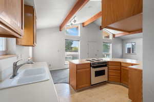 Kitchen with white stove, a sink, healthy amount of natural light, and light countertops