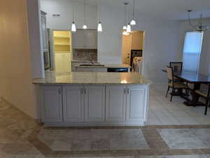 Kitchen featuring a sink, a peninsula, independent washer and dryer, baseboards, and light stone counters