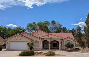 Mediterranean / spanish-style house featuring stucco siding, concrete driveway, a tile roof, an attached garage, and fence
