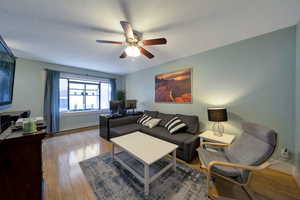 Living area featuring a ceiling fan, wood style flooring, two tone paint.