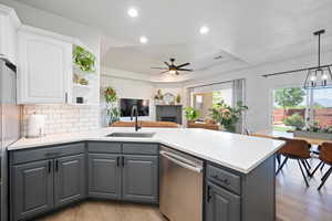 Kitchen featuring stainless steel dishwasher, gray cabinets, a sink, a ceiling fan, and white cabinetry