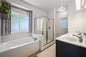 Full bath with a stall shower, a bath, wood finished floors, and double vanity