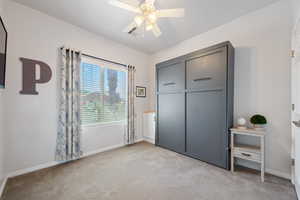 Unfurnished bedroom featuring light carpet, baseboards, and ceiling fan