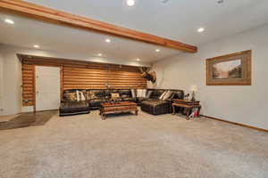 Carpeted living room featuring recessed lighting, log walls, beamed ceiling, and baseboards