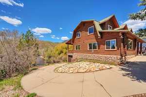 View of side of home with log exterior, a gambrel roof, stone siding, and metal roof