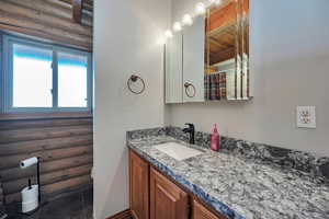 Bathroom with rustic walls, vanity, wooden ceiling, and beam ceiling