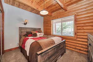 Bedroom with carpet flooring, beamed ceiling, wood ceiling, baseboards, and log walls