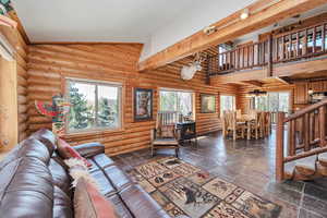 Living area with a wood stove, log walls, and stone tile floors