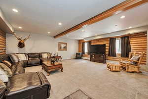 Living area with log walls, recessed lighting, carpet flooring, beamed ceiling, and a wood stove