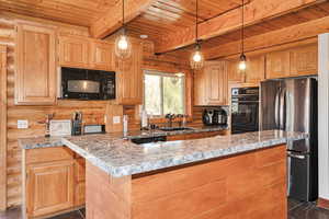 Kitchen featuring rustic walls, black appliances, a sink, wood ceiling, and beam ceiling