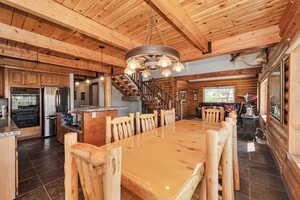 Dining room with a wood stove, stairway, wooden ceiling, a chandelier, and beamed ceiling