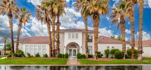 Mediterranean / spanish-style house with a tile roof, stucco siding, a front lawn, and french doors