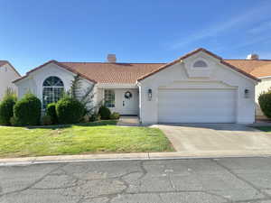 Mediterranean / spanish-style house with a tiled roof, stucco siding, a chimney, an attached garage, and a front yard