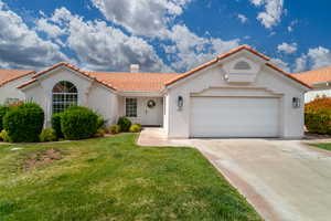Mediterranean / spanish home featuring a tiled roof, a chimney, stucco siding, driveway, and a garage
