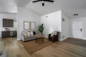 Living area with a ceiling fan, light wood-type flooring, high vaulted ceiling, and baseboards