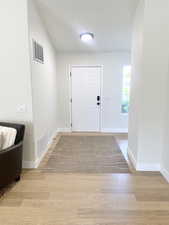 Foyer entrance with light wood finished floors and vaulted ceiling