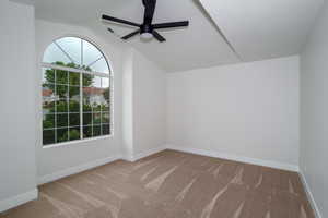 Spare room with carpet, a ceiling fan, lofted ceiling, and baseboards