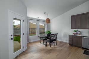 Dining space with light wood finished floors, lofted ceiling, and baseboards