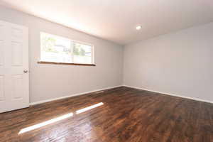 Spare room with dark wood-type flooring, baseboards, and recessed lighting