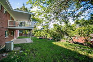View of yard featuring a patio, a balcony, and central AC unit