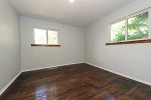 Empty room featuring baseboards and dark wood-style floors