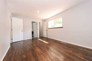 Unfurnished bedroom with dark wood-type flooring, baseboards, and recessed lighting