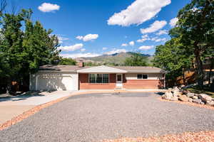 Ranch-style house featuring brick siding, a mountain view, a garage, driveway, and a chimney