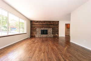 Unfurnished living room with wood finished floors, a fireplace, and baseboards