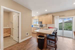 Roper Pole Barn | Conditioned Use |Kitchen featuring light brown cabinets, stainless steel appliances, light countertops, a breakfast bar area, and light wood-style floors