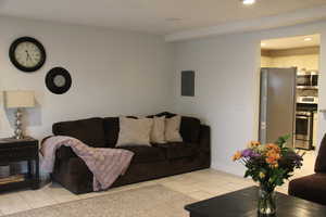 Living area with electric panel, recessed lighting, and baseboards