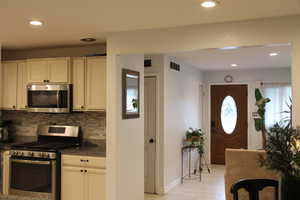 Kitchen featuring stainless steel appliances, backsplash, recessed lighting, baseboards, and white cabinets
