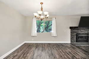 Unfurnished dining area with a chandelier, baseboards, and wood finished floors