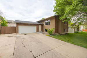 Split level home with concrete driveway, brick siding, and an attached garage