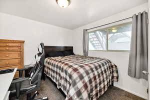 Bedroom with dark carpet and baseboards