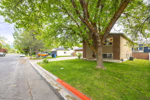 View of front of house featuring concrete driveway, a front lawn, brick siding, and central AC