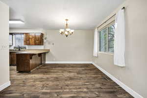 Kitchen with plenty of natural light, a chandelier, a breakfast bar area, and a peninsula