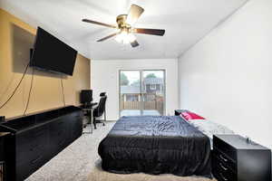 Carpeted bedroom featuring access to exterior, an office area, and ceiling fan