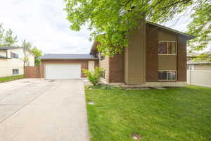 Split level home with a garage, brick siding, and concrete driveway